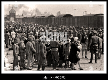AUSCHWITZ-BIRKENAU HOLOCAUST PRISONERS ARRIVAL- A stark vision of a hell on earth. 1944, Nazis 'grading' (life or peremptory death) unsuspecting recently arrived adults and children on rail concourse, outside entrance to Auschwitz-Birkenau extermination death camp. The infamous Auschwitz camp was started by order of Adolf Hitler in 1940's during the occupation of Poland by Nazi Germany during World War 2, further enabled by Heinrich Luitpold Himmler the Reichsführer of the Schutzstaffel, and leading member of the Nazi Party of Germany Stock Photo