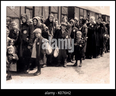 Auschwitz-Birkenau Jewish women and children wearing Nazi designated yellow stars arrive at WW2 German Nazi Concentration & Extermination camp. Jewish children made up the largest group of those deported to the camp. They were usually sent there along with adults, beginning in early 1942, as part of the “final solution of the Jewish question”—the total destruction of the Jewish population of Europe...Auschwitz concentration camp was a network of German Nazi concentration camps and extermination camps operated by the Third Reich in Polish areas annexed by Nazi Germany during World War II. Stock Photo