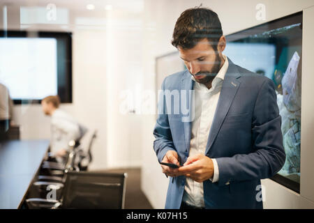 Handsome young businessman in blue suit holding mobile phone Stock Photo