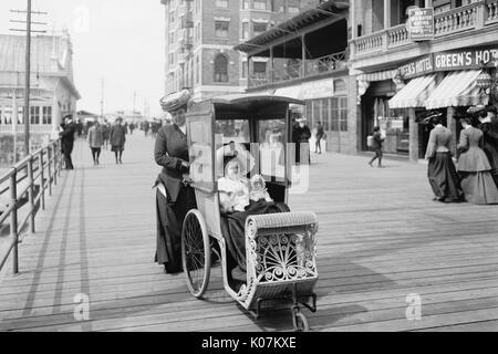 Girl with her doll in a wheeled chair on the Boardwalk, Atla Stock Photo