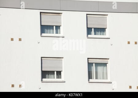 Windows with closed shutters on a white House Wall Stock Photo
