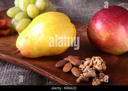 Fresh organic fruits on wood Serving tray. Assorted apple, pear, grapes, dried fruits and nuts. Stock Photo