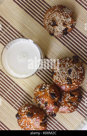 Biscuits on the table with sesame seeds, raisins and a glass of milk. Set Stock Photo