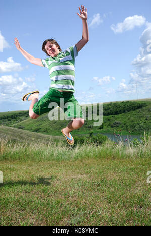 Young Man jumps in the air with prairie in background Stock Photo