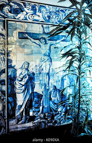 A large religious artwork of blue ceramic tiles (azulejos) depicts Jesus Christ on the cross and decorates an outdoor wall at the Convent of Nossa Senhora da Esperanca in Ponta Delgada on Sao Miguel Island in the Azores, an autonomous region of Portugal in the North Atlantic Ocean. Stock Photo