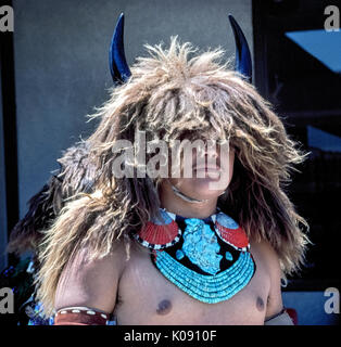 Horns protruding from a headdress of buffalo hair indicate that this Native American male is participating in a traditional Buffalo Dance that is a highlight at some of the Indian powwows held by the 19 Pueblo tribes that reside in the state of New Mexico, USA. The dancer also wears an impressive necklace of turquoise and painted seashells. Stock Photo