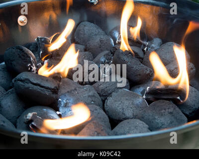 Charcoal Briquettes in a barbecue with lit firelighters Stock Photo