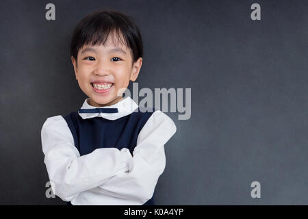 Asian Chinese little girl standing in front of blackboard in isolated black background Stock Photo
