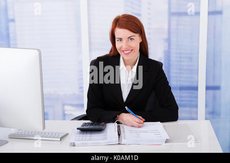Portrait of confident businesswoman calculating tax at office tax Stock Photo
