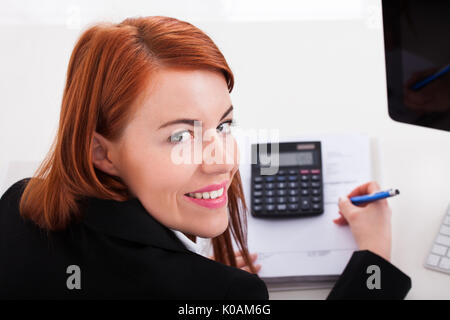 Cropped image of businesswoman using calculator while working at office desk Stock Photo