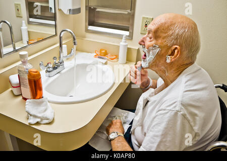 Elderly Male Patient in Wheelchair Shaving at Sink Stock Photo