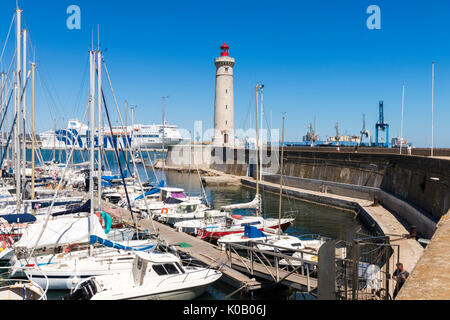 Boats in the port of Sete, Southern France, with the Phare du Mole Saint-Louis lighthouse and the GNV Majestic in the background Stock Photo