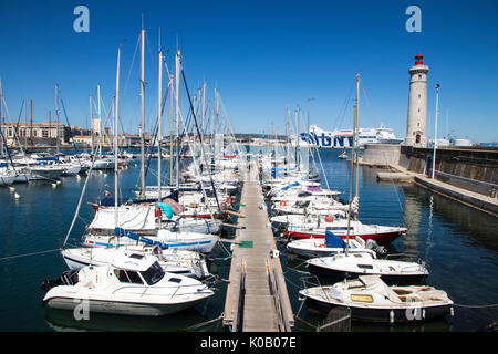 Boats in the port of Sete, Southern France, with the Phare du Mole Saint-Louis lighthouse and the GNV Majestic in the background Stock Photo