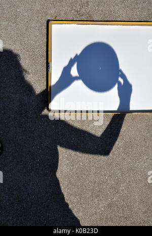 Shadow of Young Woman Positioning a Pinhole Camera Capturing the Crescent Sun during the Solar Eclipse on August 21, 2017 Stock Photo