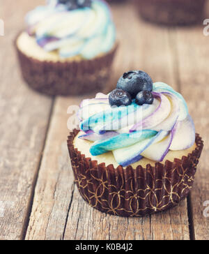 Festive cupcake on a wooden background with bright cream and blueberry rustic style. Stock Photo