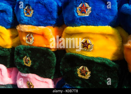 Rows of russian winter hats of different colors with army emblems at the street market at Old Arbat street, iconic popular souvenir from Russia. Stock Photo