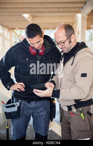 Carpenters Using Digital Tablet At Site Stock Photo