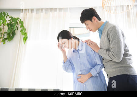 Pregnant wife having headache and her husband worried Stock Photo