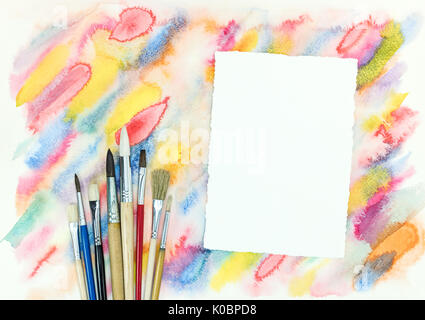 empty paper sheet with various paintbrushes over colorful diagonal watercolor strokes background Stock Photo
