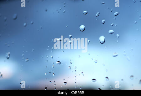 Window with raindrops, dark blue clouds behind Stock Photo