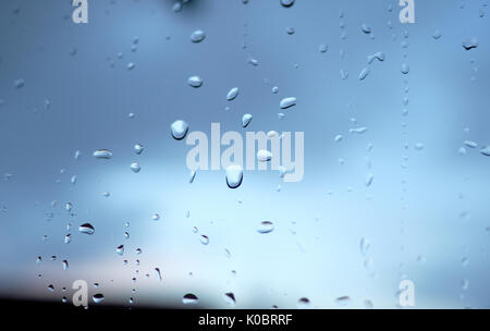 Raindrops on a window, dark clouds behind Stock Photo