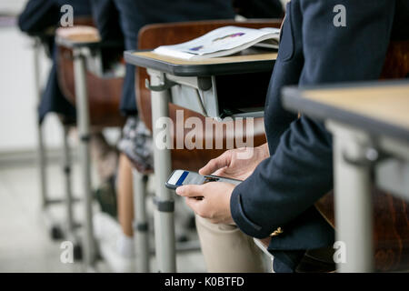 School boy using smartphone in class Stock Photo
