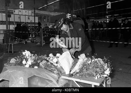 British Rail porter, Andreas Polychardou, places flowers among the bunches left by passers-by and relatives of the King's Cross Underground Station fire. Stock Photo