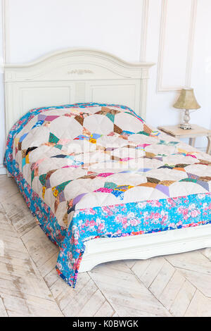 retro, housekeeping, interior concept. antique white bed covered with handmaded blanket performed from different cotton pieces various shade and color Stock Photo