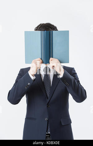 Bust shot of young businessman covering his face with an open book Stock Photo