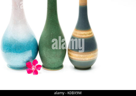 Modern pottery vases with beautiful patterns, pink flower in front of vases isolated on white background Stock Photo