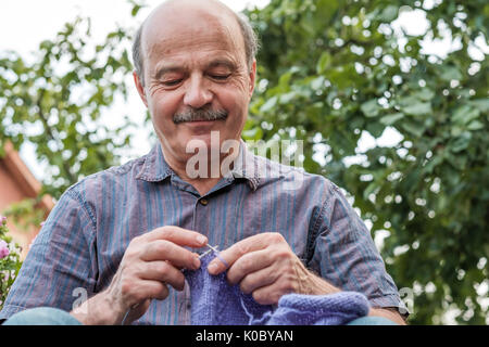 people and needlework concept - woman hands knitting with needles and red yarn Stock Photo