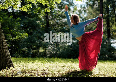 Sporty fit caucasian woman doing asana Virabhadrasana 2 Warrior pose posture in nature. Stock Photo