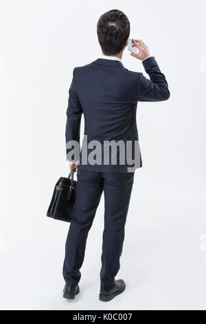 Back of young businessman in suit standing talking on cellphone Stock Photo