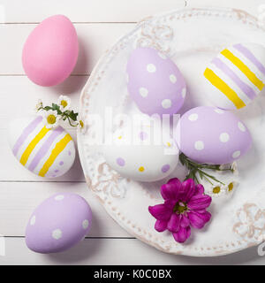 Colorful Easter eggs and flowers of the field in the plate. Top view Stock Photo