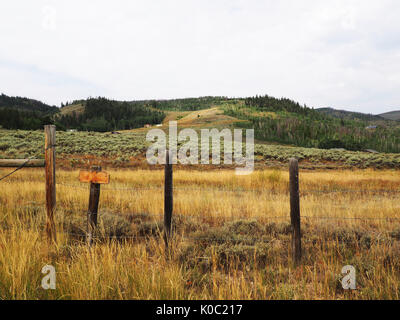 A wire fence on a prairie in Colorado.  In the back are gently rolling hills. Stock Photo