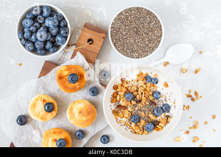 granola with yogurt and mini cheesecakes with blueberries for breakfast. Stock Photo