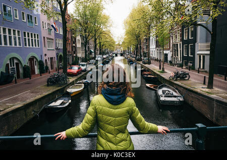 Young woman stands on the bridge and looks at the canal of Amsterdam, Netherlands Stock Photo
