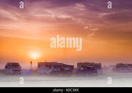 The sun rises over a misty campsite in the UK at dawn on an August morning. Stock Photo