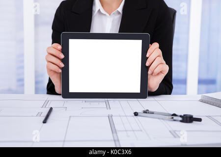Midsection of young female architect displaying blank screen of digital tablet in office Stock Photo
