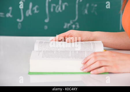Cropped image of young university student reading book in classroom Stock Photo