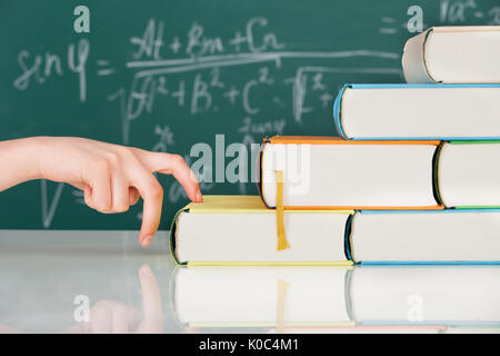 Cropped image of woman's hand climbing stack books in classroom Stock Photo
