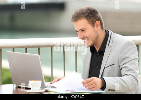 Single happy executive consulting on line content in a laptop sitting in a coffee shop Stock Photo