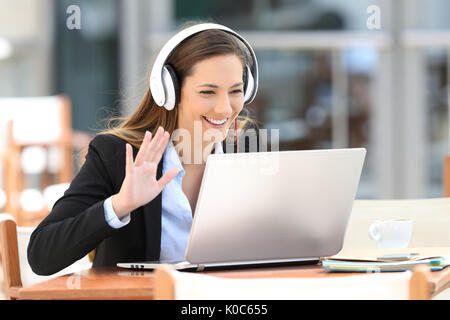 Executive having a video call with a laptop and headphones in a coffee shop Stock Photo