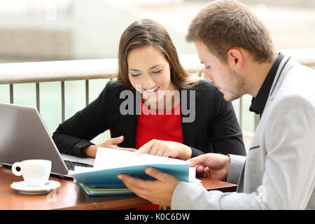 Two happy executives consulting documents working together in a coffee shop Stock Photo