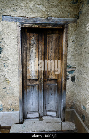Weathered wooden door with a metallic rusty lock textured with white paint chipped and peeling Stock Photo