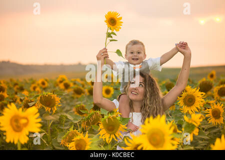 Mother with baby son in sunflower field Stock Photo