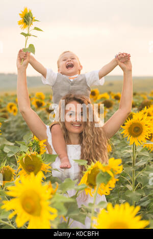 Mother with baby son in sunflower field Stock Photo