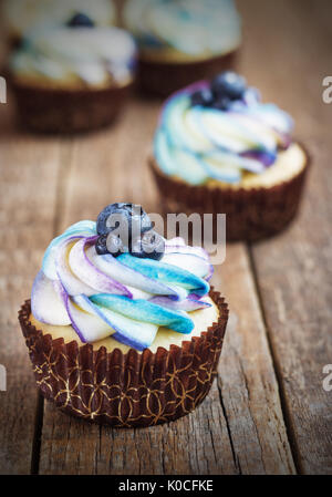 Festive cupcake on a wooden background with bright cream and blueberry rustic style. Stock Photo