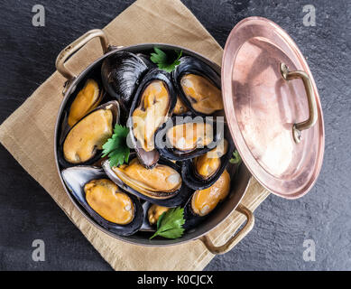 Boiled mussels in copper pan on the graphite background.
