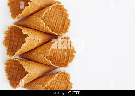 Several waffle cones lined in tower, smile, or even row, top view, isolated on white background. Stock Photo